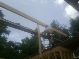 Carpenter setting a ridge beam over a new addition frame — Ice Dam Removal by Roofing Brothers in Guin