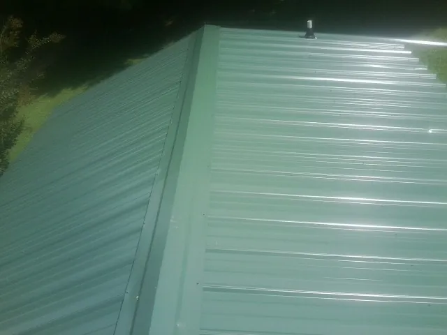 New green metal panels meeting at the ridge of a roof in Guin