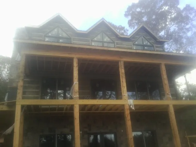 Dormers and porch framing on a large log home under construction — Roof Coating work by our crew in Guin