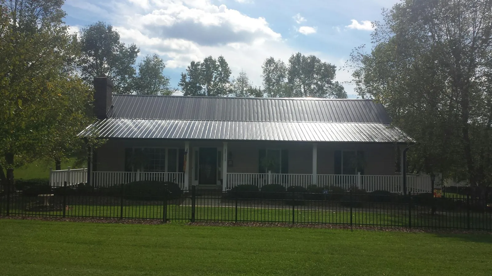 Gray metal roof on a brick ranch with a full width front porch — Gutter Guard Installation work by our crew in Guin