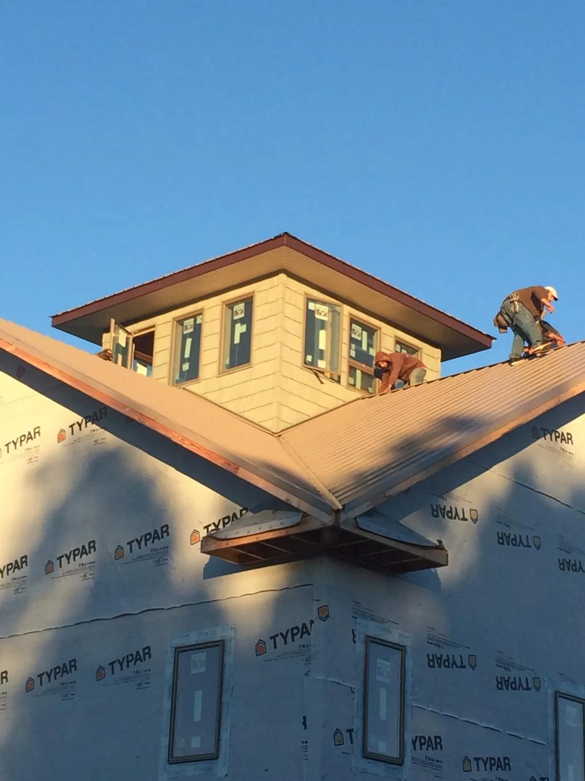 Roofers working around a rooftop cupola on a new metal roof at sunset — Roof Waterproofing in Guin by Roofing Brothers